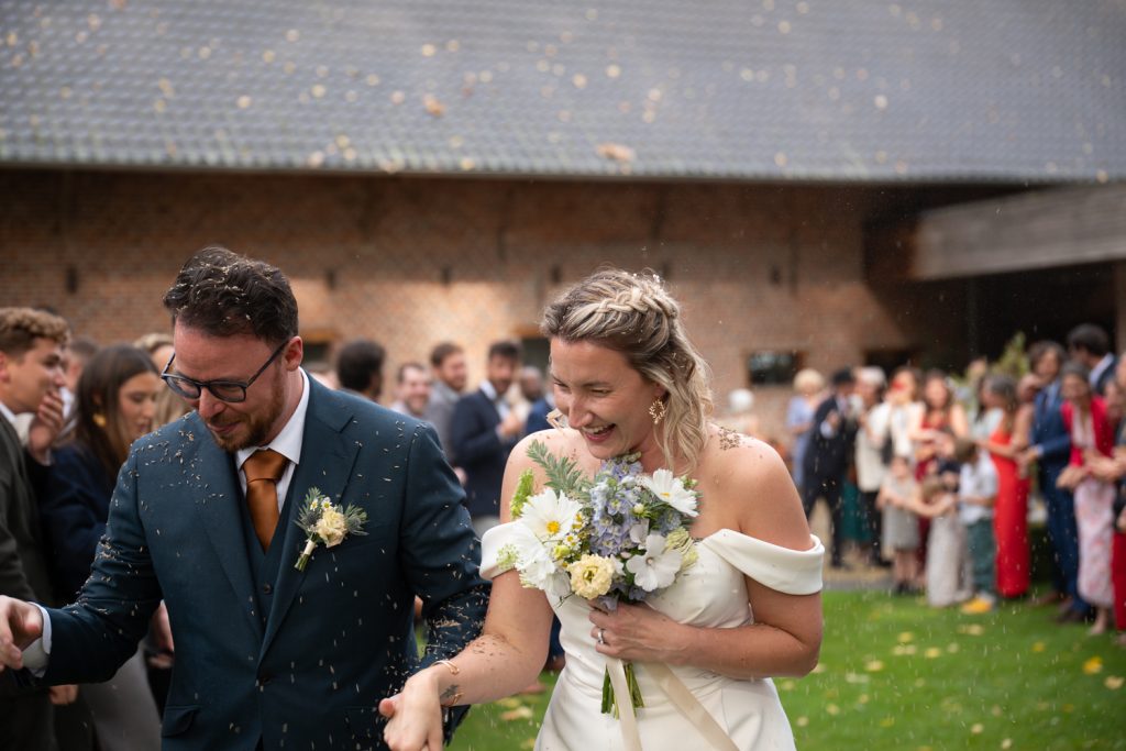 photographe mariage belgique les mariés sortent sous pluie de lavande et haie d'honneur après la cérémonie à Brunehaut