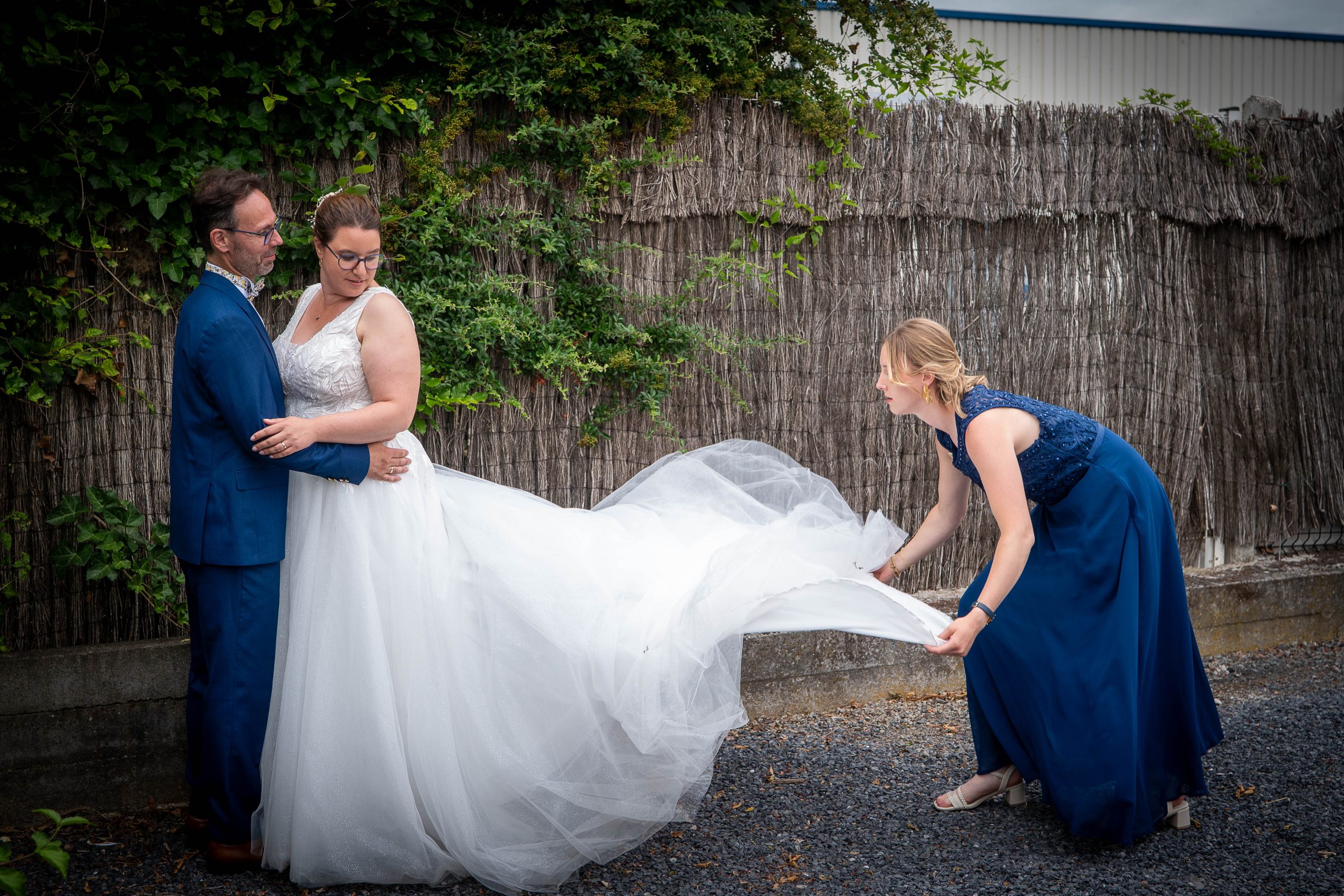 photo couple mariage Mélanie et Mickael la niece repositionne la traine de la robe