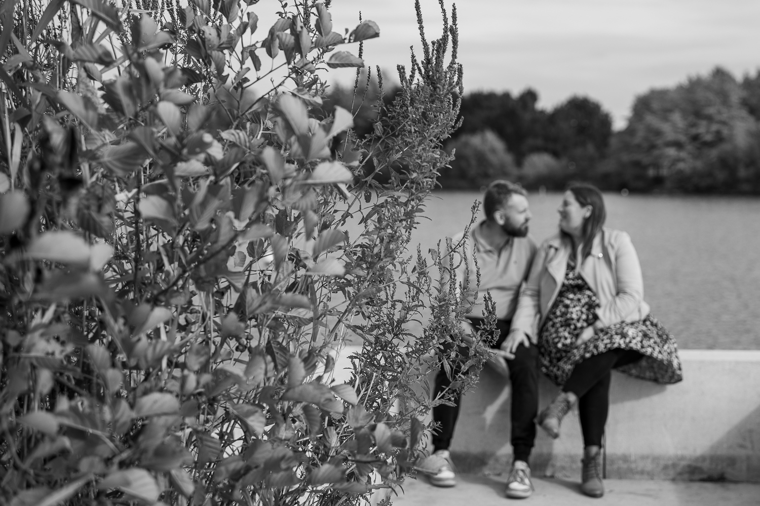 couple assis qui discute derrière un arbuste