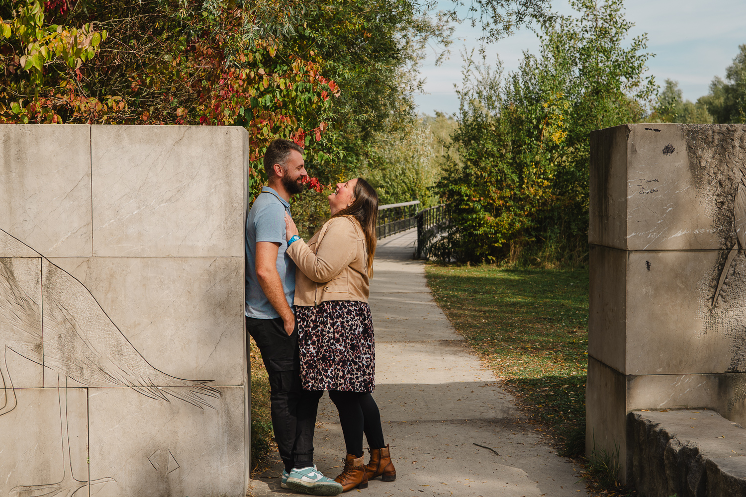 couple qui rit joyeusement adossé contre un mur