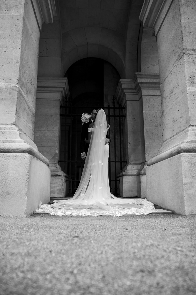 mariés de dos sous les arcades en pierre