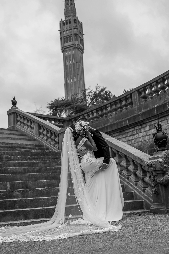 photographe mariage lille marié qui bascule la mariée cachée par son bouquet face au beffroi