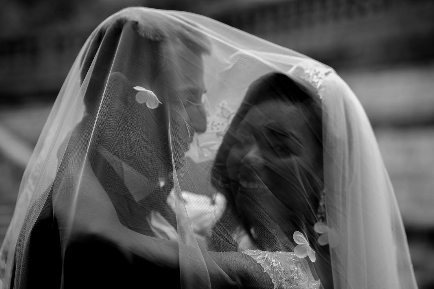 mariés enlacés dont les têtes sont sous le voile de la mariée