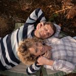 couple allongé sur herbe dans une foret qui se tiennent la main