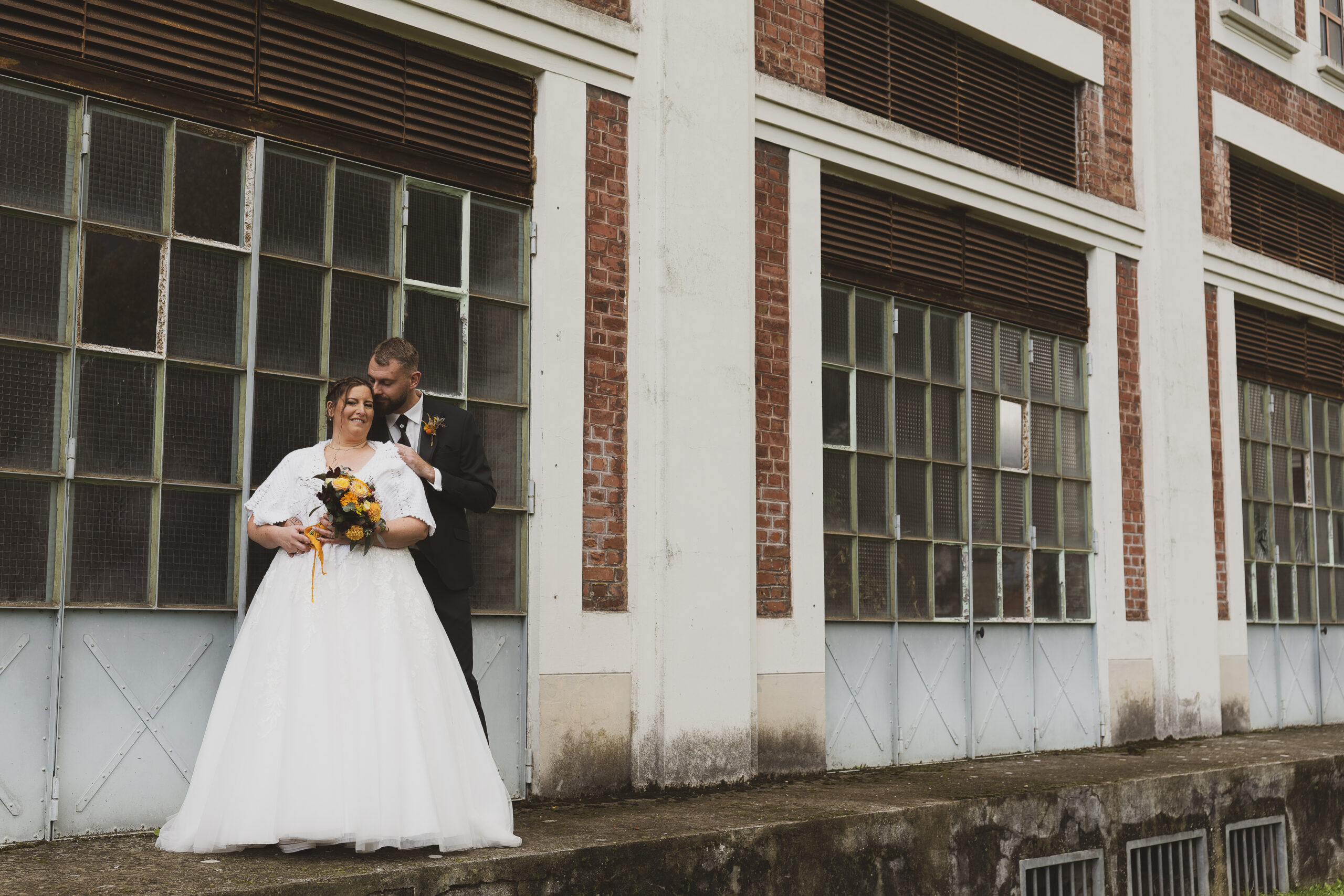 photo de couple marié dans un site minier qui posent devant batiment industriel