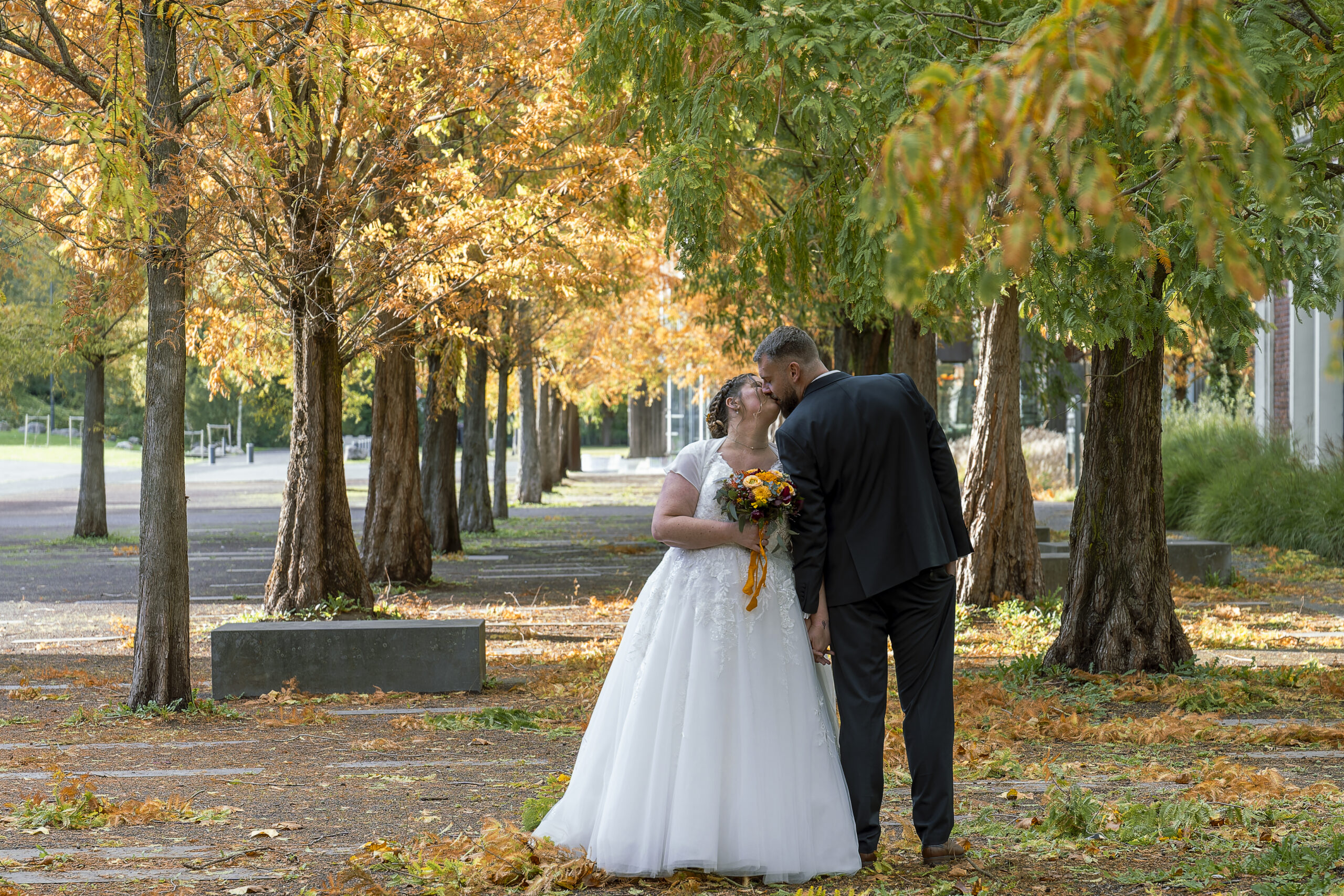photo de couple marié dans un site minier, au milieu d'une allée d'arbres jaunes et verte automne
