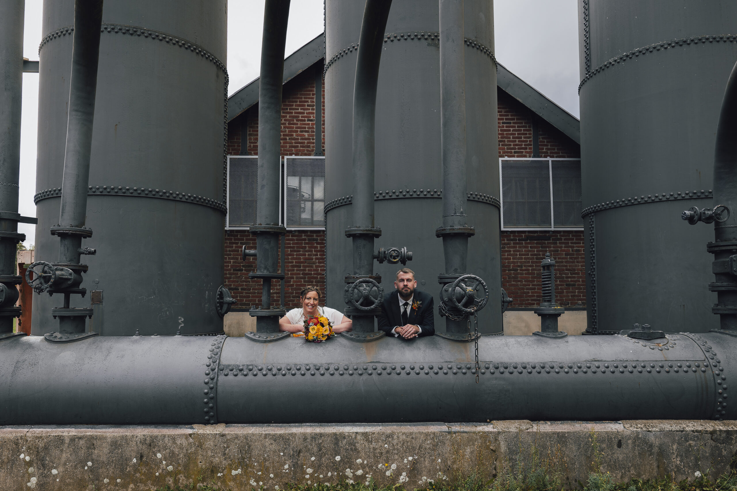 photo de couple marié dans un site minier appuyé sur une tuyauterie miniere