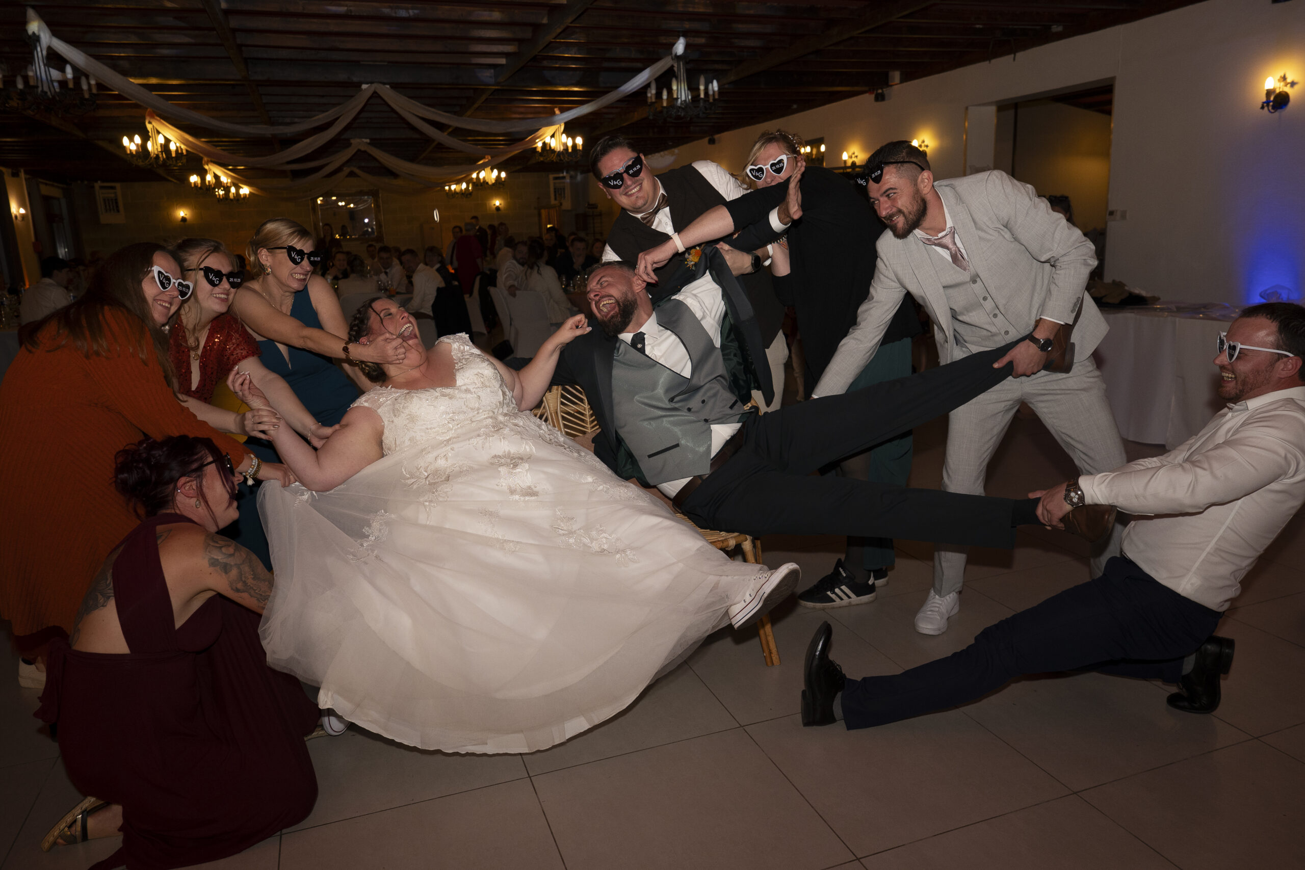 photobomb des mariés avec leurs amis qui leur tirent les membres dans la salle de reception