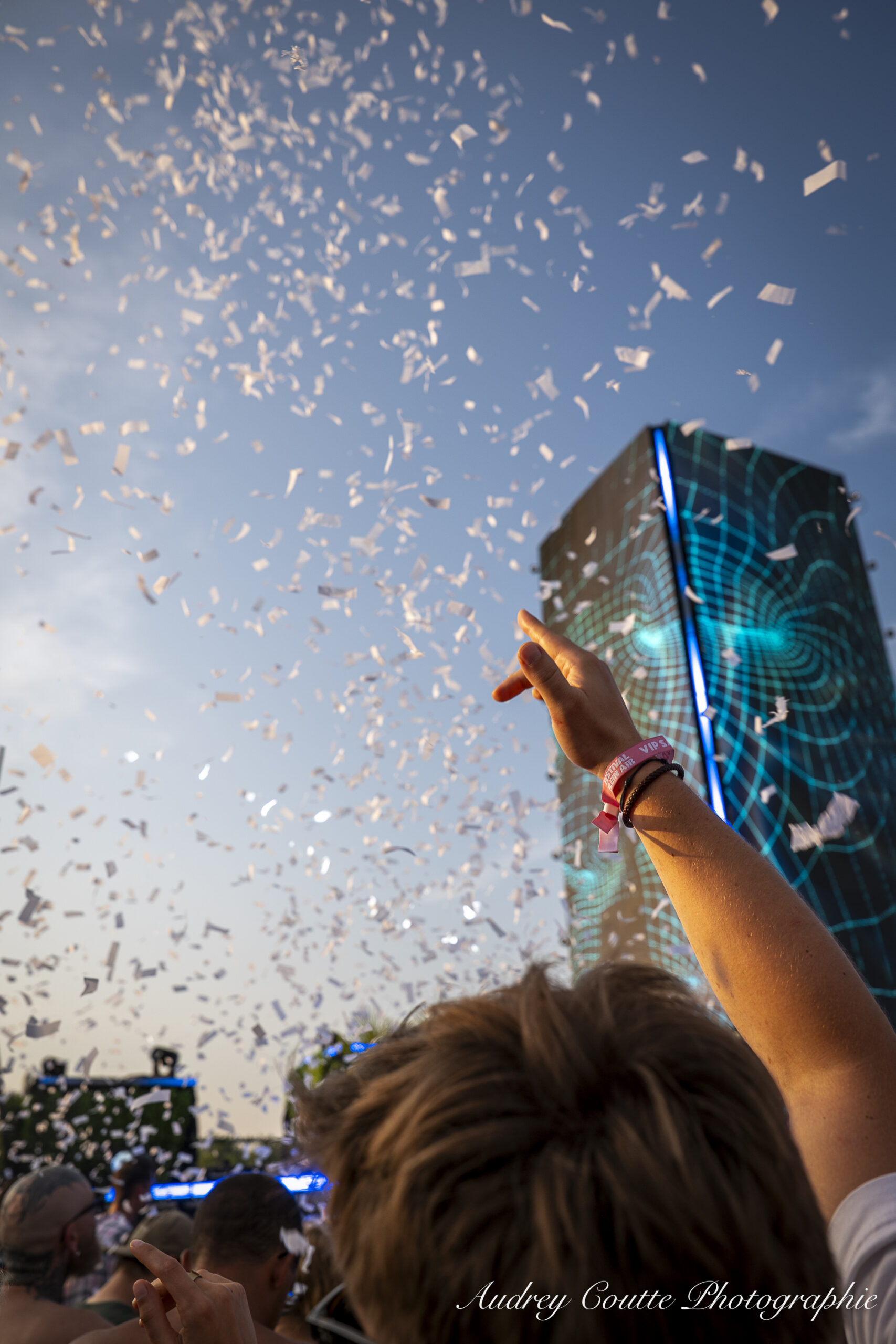 festivalier qui met la main en l'air dans le nuage de confettis